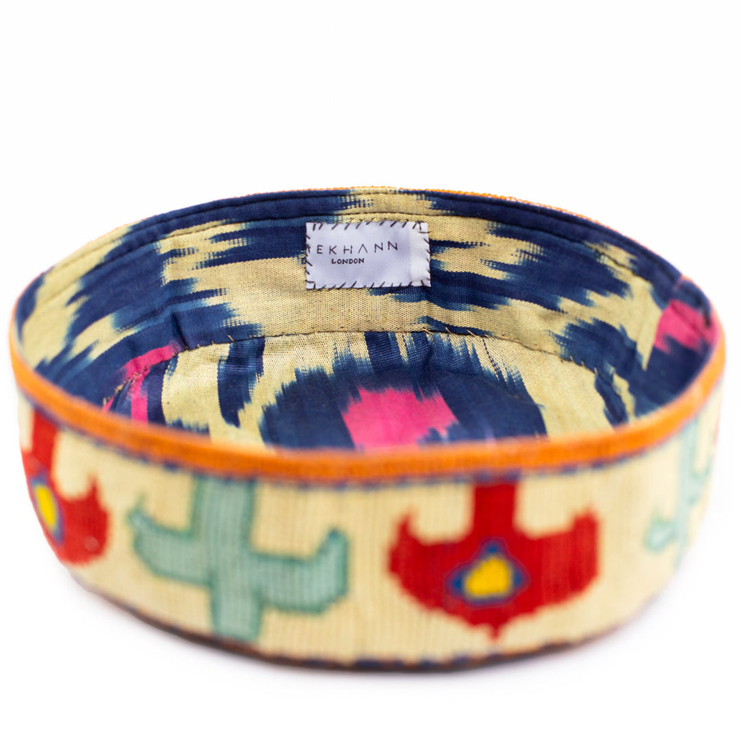 Full frame view of Mekhann's geometric cream skull cap, showing a view of how the ikat lining complements the colours of the external embroidery.