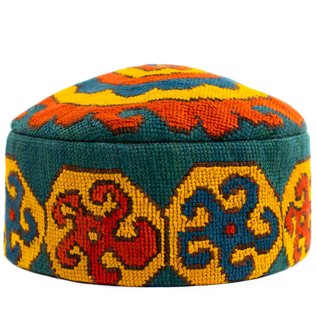 Front view of Mekhann's geometric green skull cap, the embroidered patterns showcase the attention to the geometric patterns in green, yellow, and orange.
