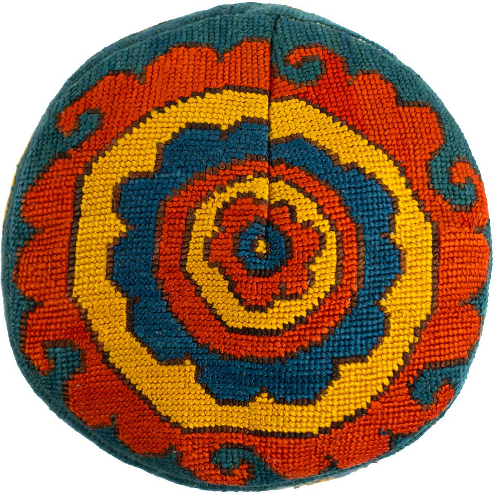 Top view of Mekhann's geometric green skull cap, showing a blue, yellow, and green geometric spiral design.