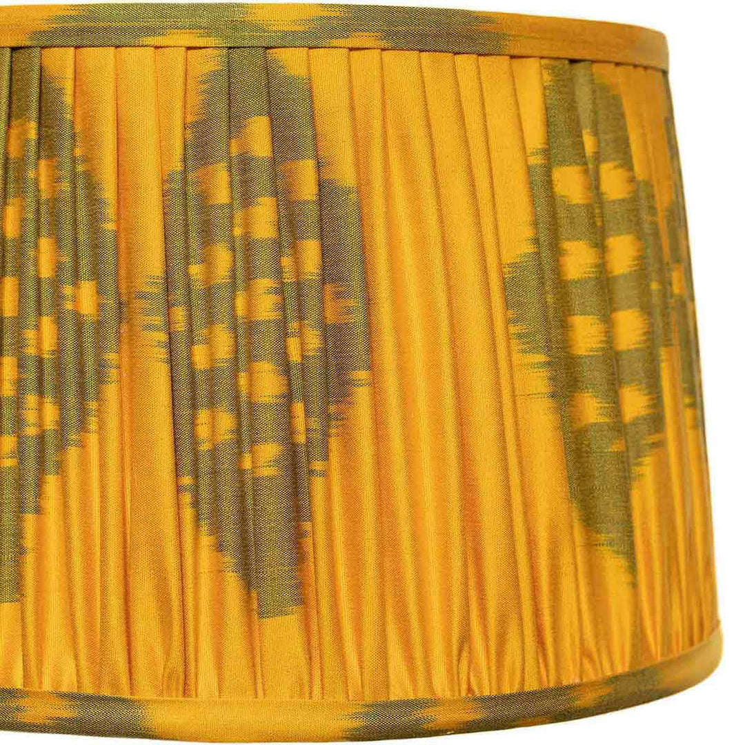 Close-up of Mekhann's lampshade with a green ikat pattern on a saffron base, highlighting the handcrafted quality and vibrant hues.