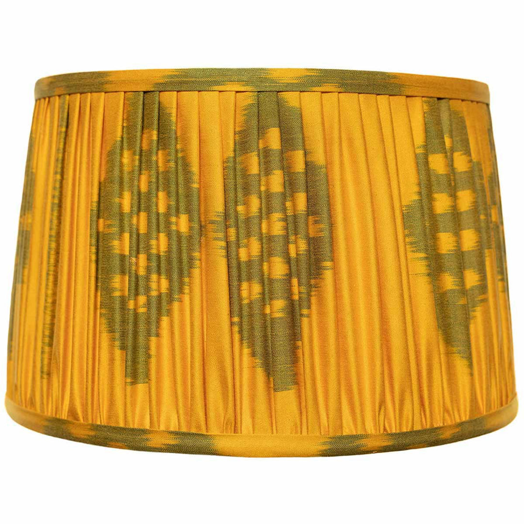 Front view of Mekhann's saffron ikat silk lampshade, featuring a green ikat pattern, hand-pleated with natural dyes.