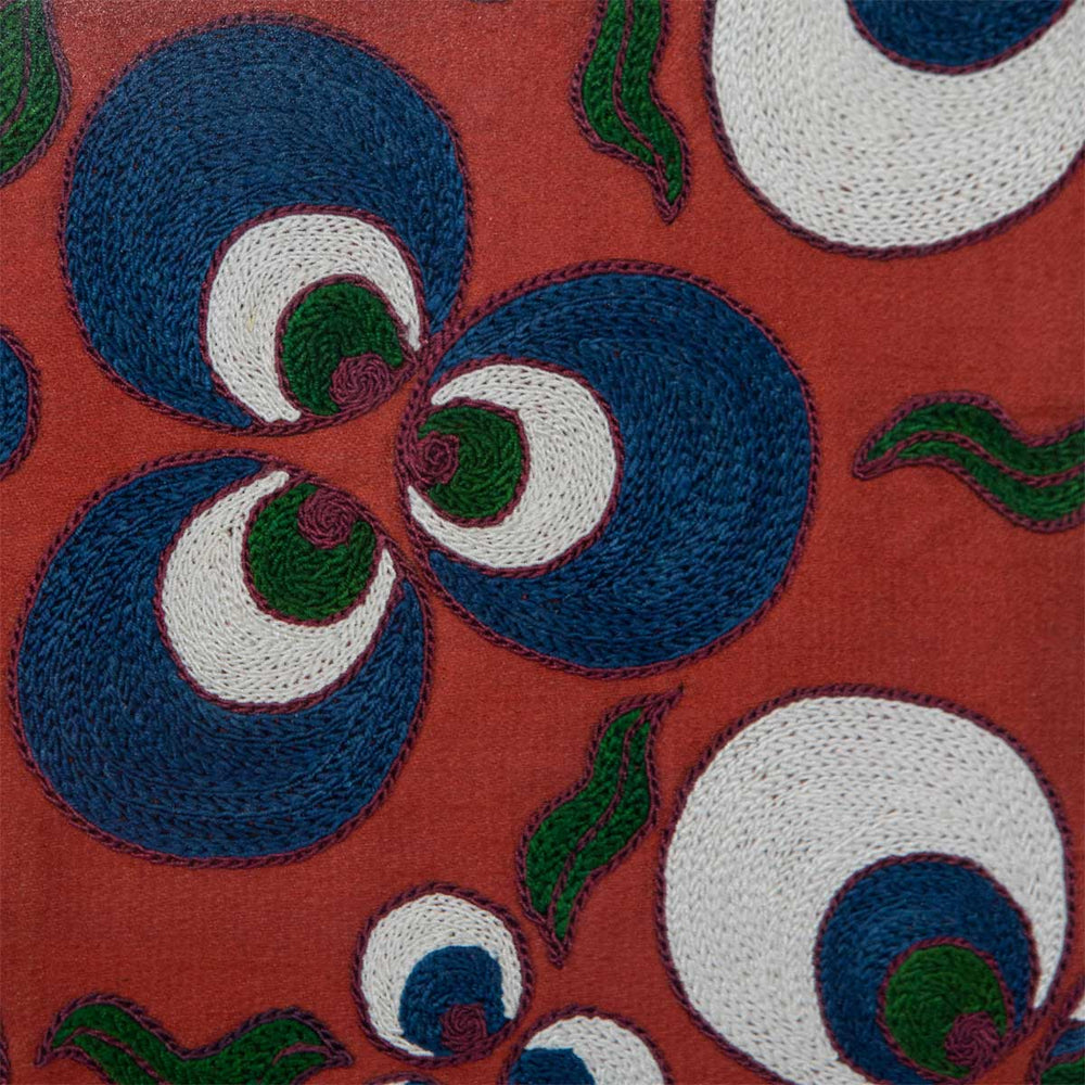 Close up view of Mekhann's maroon silk cintamani artwork, revealing a dark maroon embroidered outline of the blue and white Cintamani patterns all set on a base on maroon silk.