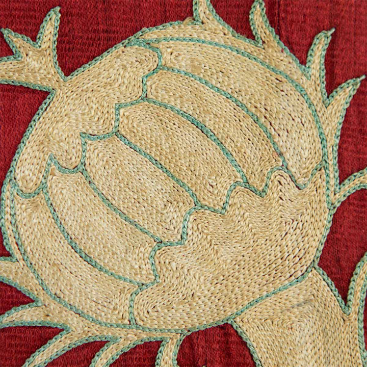 Detailed of Mekhann's maroon grape vines throw, showing a cream grape design motif with a light blue outline to make the details visible on contrast with the bright maroon silk base.