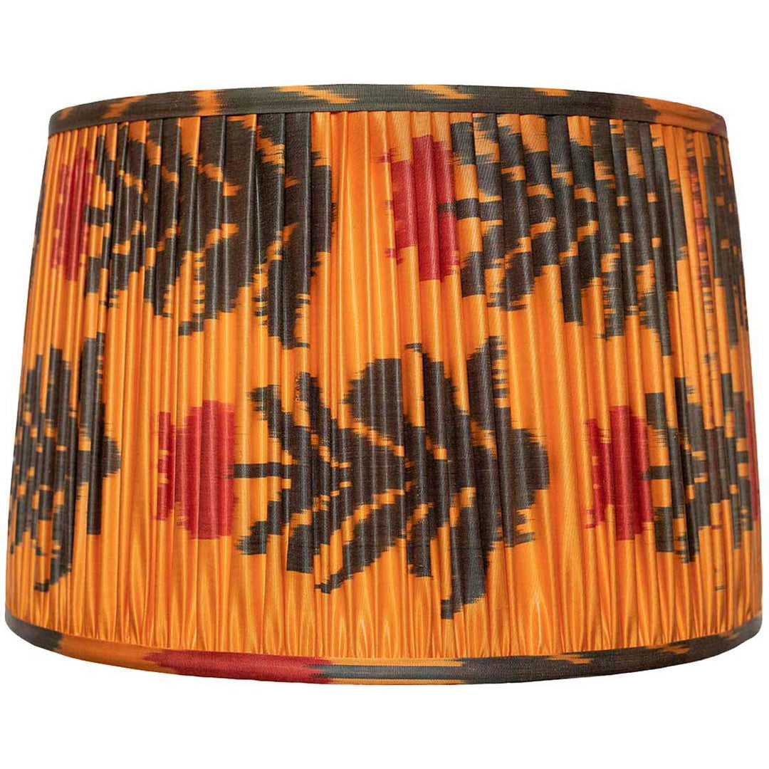 Mekhann's vibrant orange silk lampshade with black floral ikat patterns, front view showcasing handcrafted pleating.