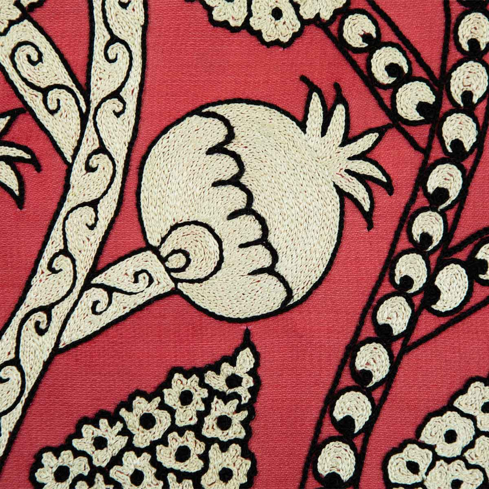 Close up view of Mekhann's hand embroidered, pink silk artwork, showing one of the cream pomegranate motifs up close, revealing the intricate embroidery techniques. 