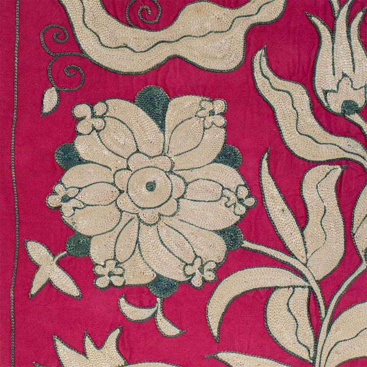 Close up view of Mekhann's pink ottoman vines runner, showing a flower motif and the detailed patterns around in on a base of pink silk.