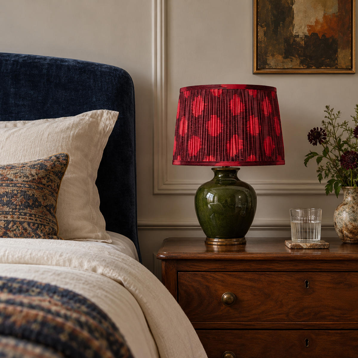 Polka Dot lampshade styled on a green ceramic base beside an indigo headboard; illustrative bedroom setting.