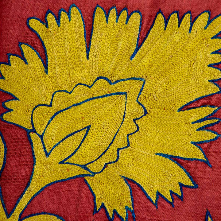 Detailed view of Mekhann's red botanical throw, showing how the colours complement each other and the contrast in texture between the yellow silk embroidery and the red silk base.