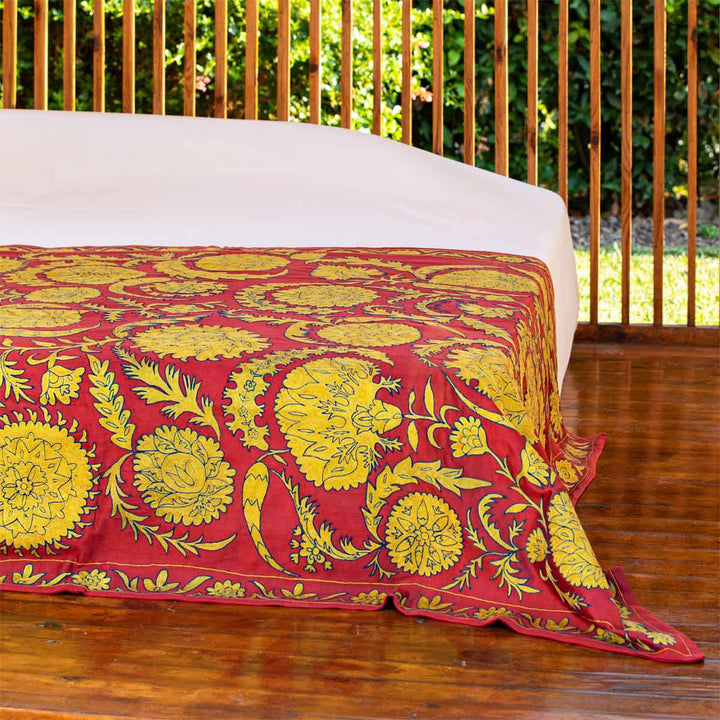 In use view of Mekhann's red botanical throw, showing a winder angle of the bed spread where we can see how it would look on full display.