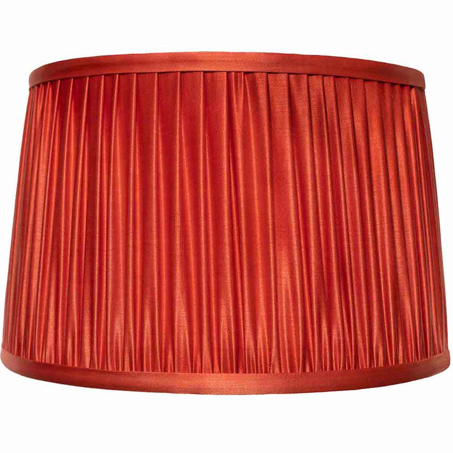 A pleated fabric lampshade in a warm rust red color, shown against a plain white background.