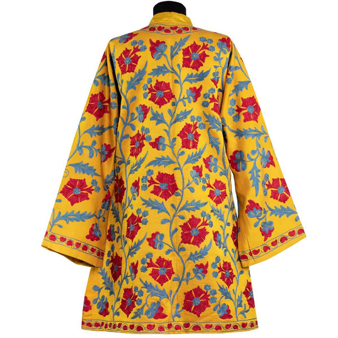 Back view of Mekhann's embroidered botanical kaftan in saffron, showcasing how the botanical pattens wrap around onto the back of the kaftan, creating a consistent hand embroidered kaftan.