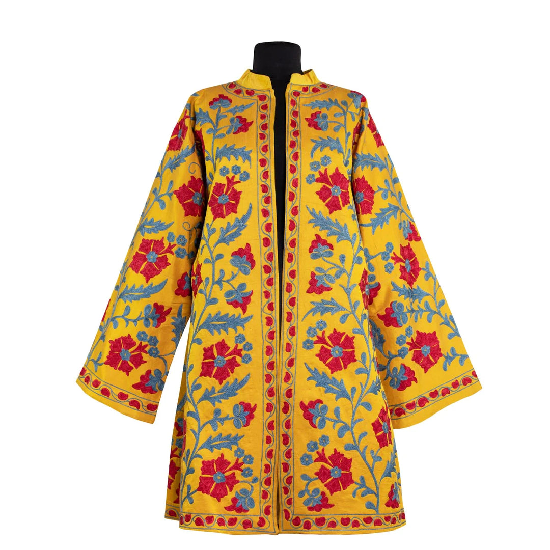 Front view of Mekhann's embroidered botanical kaftan in saffron, with a blue and red hand embroidered botanical display on a silk saffron base. 