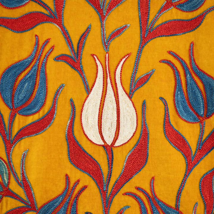 Close up view of Mekhann's embroidered velvet tulips kaftan in saffron, showing the hand embroidered tulip in white with a delicate red outlining.