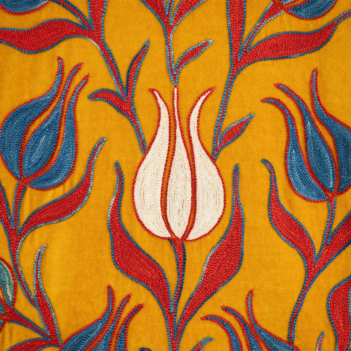 Close up view of Mekhann's embroidered velvet tulips kaftan in saffron, showing the hand embroidered tulip in white with a delicate red outlining.
