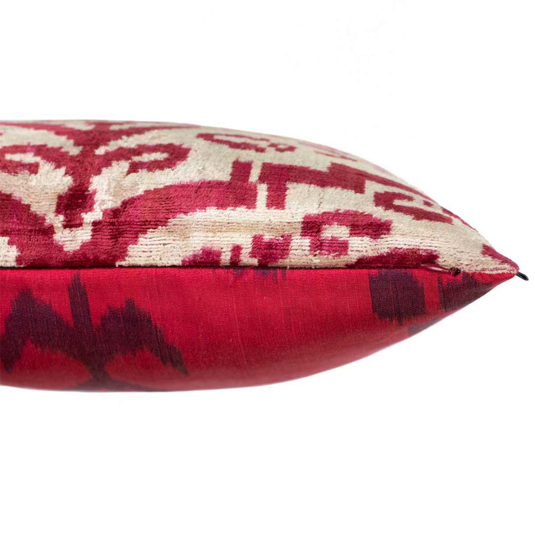 Side view of Mekhann's abstract maroon pattern velvet cushion, where we can see where the front of the velvet cushion meets the back ikat fabric. We can also see a zip that is used to access the cushion pad.
