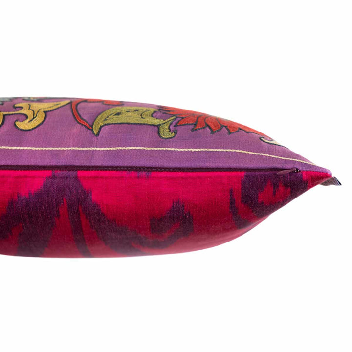 Side view of Mekhann's pink sunflower embroidered cushion, showing where the pink ikat lining meets the front face of the cushion. We can also see the purple zip that would allow for easy removal of a cushion pad.