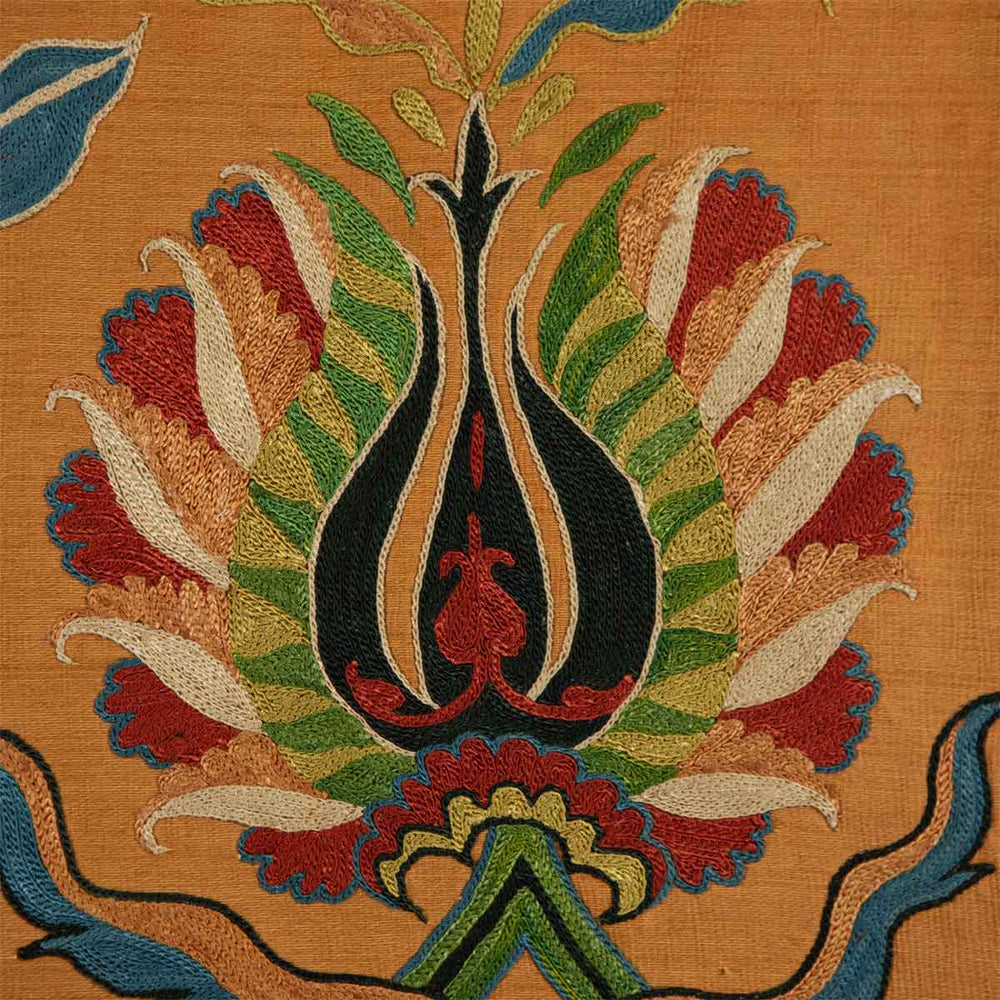 Detailed view of Mekhann's tulip caramel petite throw, with embroidery of tulips in deep reds and vibrant greens on a warm caramel coloured silk background.