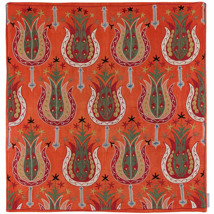 Front view of Mekhann's clementine tulip petite throw, with a repeating pattern of ornate tulips and decorative elements, all have been hand embroidered onto a canvas of bright orange coloured silk.