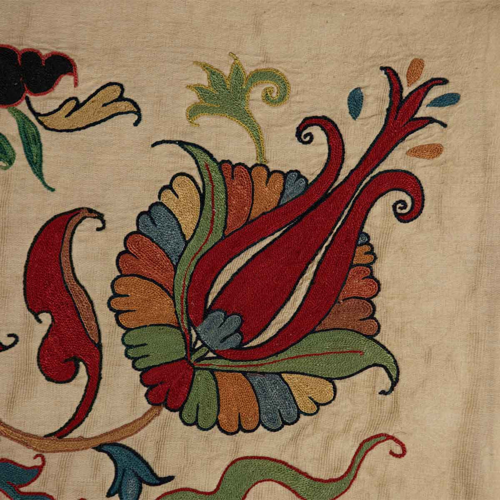Close up view of Mekhann's silk tulip petite throw, featuring the fine embroidery of the tulip motif in bright red and revealing the texture of the silk fabric.