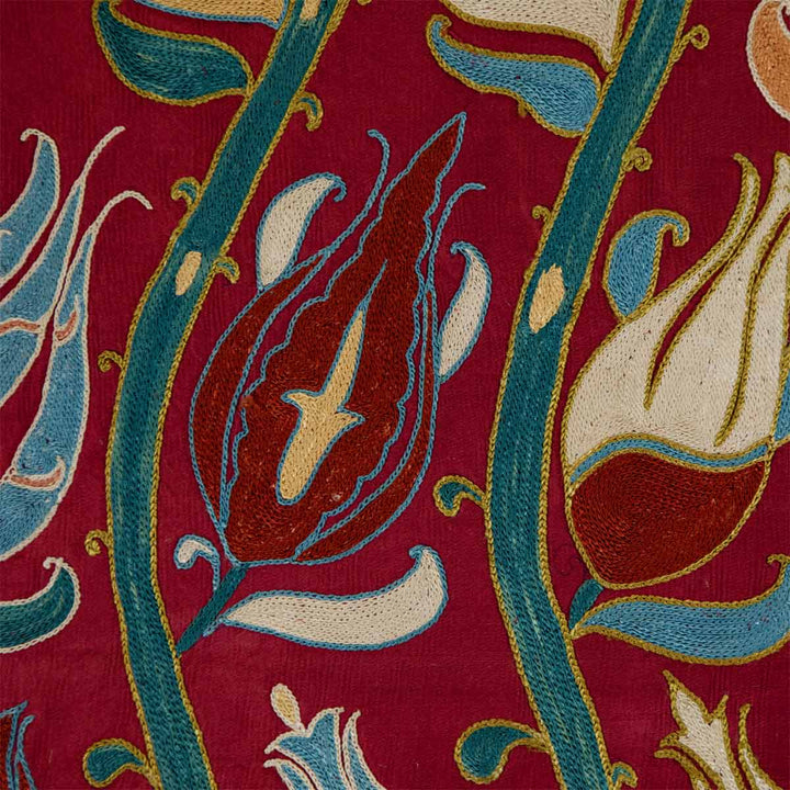 Close up view of Mekhann's maroon tulip petite throw, highlighting the intricate weave and the hand embroidery of the tulip design that complements the maroon silk base.