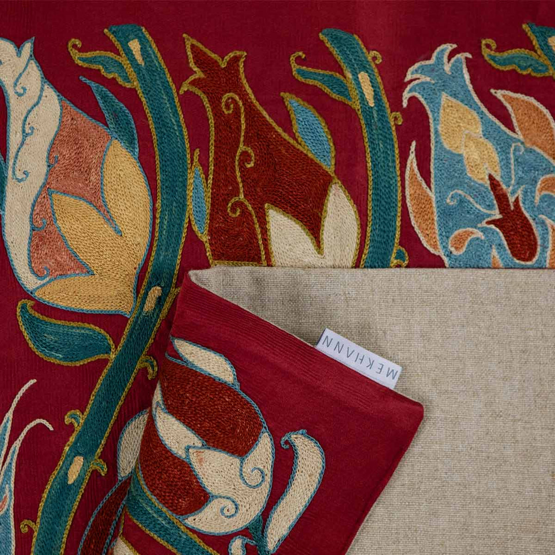 Folded view of Mekhann's maroon tulip petite throw, with the tulip embroidery adding a touch of charm and sophistication to the luxurious fabric.