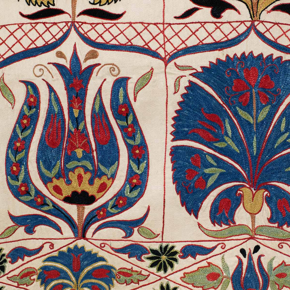 Detailed view of Mekhann's tulips and carnations throw, showing a blue tulip and carnation side by side, displaying all the hand embroidered detailed within the flowers in red and green tones.