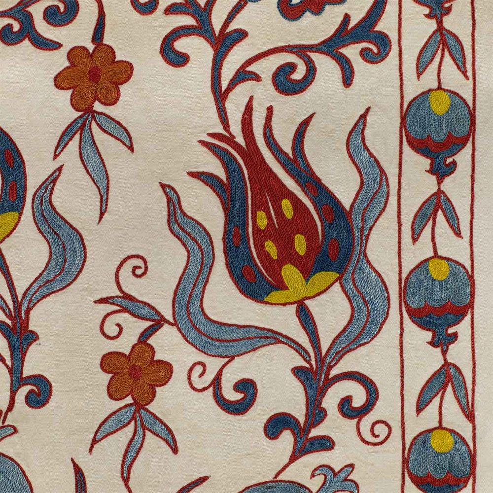 Close up view of Mekhann's cream tulips runner, showing the intricate detail of the embroidered tulips and pomegranates in the frame work of the tulip runner.