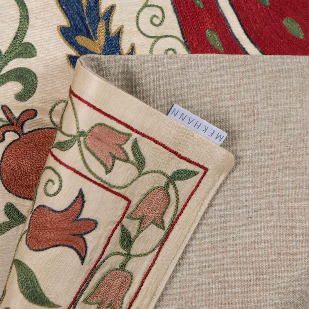 Folded view of Mekhann's cream tulips runner, showing how the beige lining complements the front of the runner and also showing the Mekhann label attached to the runner.