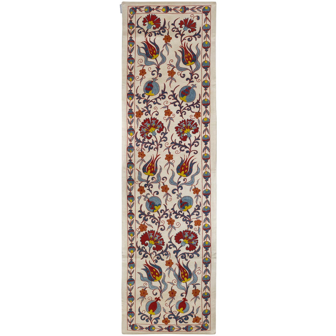 Front view of Mekhann's cream tulips runner, showing the full display of hand embroidered tulips and other floral motifs that fill the runner, all set against a cream coloured silk base.