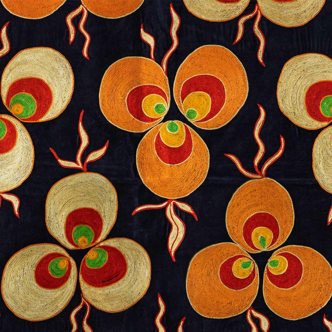 Close up view of Mekhann's navy, velvet cintamani throw. Showing the bright silk embroidery in orange, red, green and yellow cintamani patterns against the deep navy backdrop.