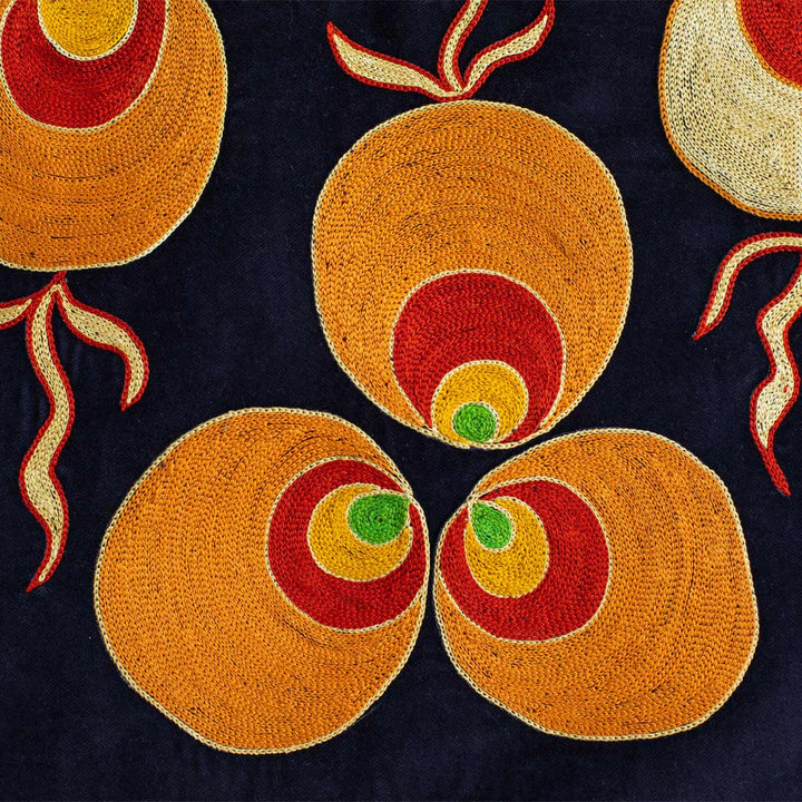 Detail view of Mekhann's navy, velvet cintamani throw, Bringing you closer the the vibrant orange silk thread used to create the cintamani pattern on a velvet navy background.