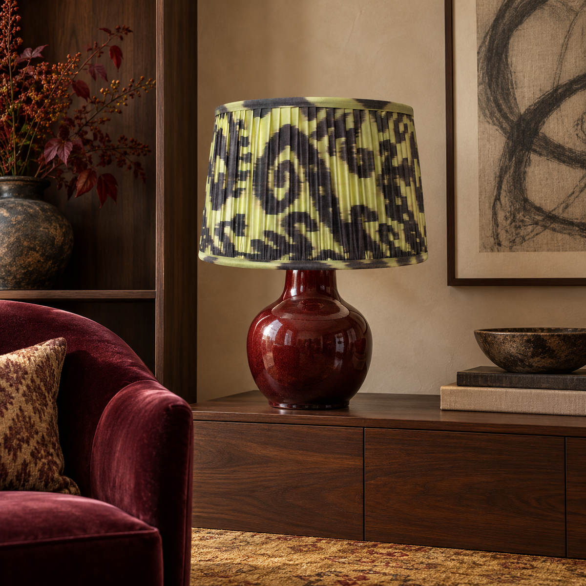 Volute lampshade styled on an oxblood ceramic base above a walnut console; illustrative sitting-room setting.