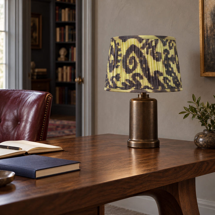 Volute lampshade styled on a bronze-toned base at a walnut writing table; illustrative study setting.