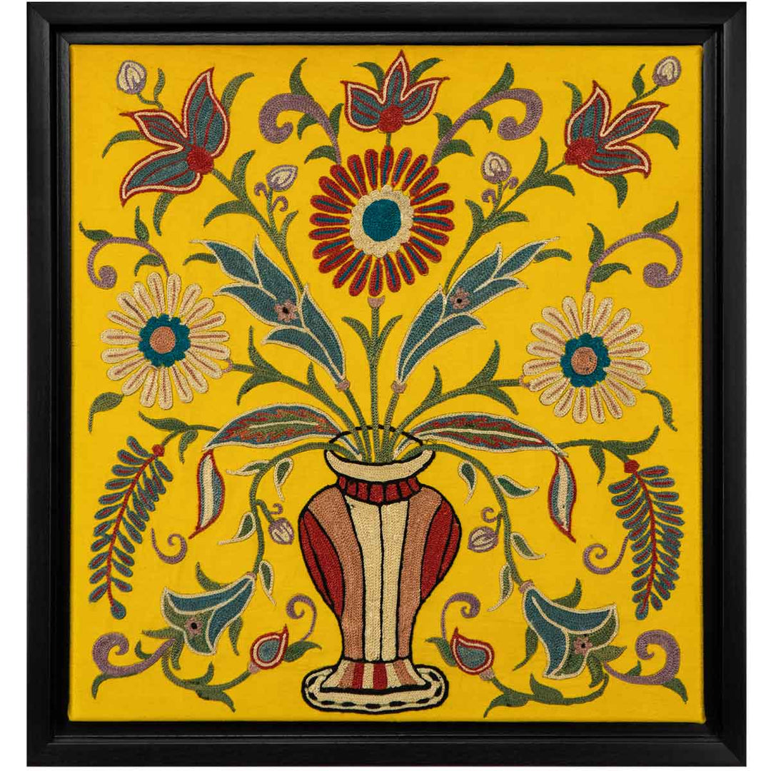 Front view of Mekhann's yellow silk artwork with hand embroidered floral shapes, Showing the full view of the embroidered flower details coming out of a vase. All of this framed in a black frame.