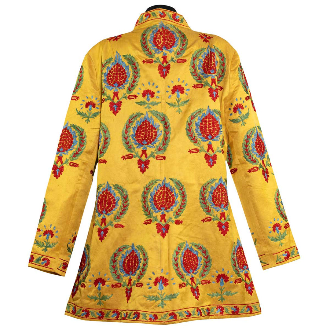 Back view of Mekhann's embroidered arabesque kaftan in saffron, revealing the consistency of the design as it travels to the back area of the kaftan. Also showcasing the matching trim on the neck, base, and wrist area on the kaftan.